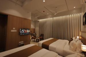 a hotel room with two beds and a flat screen tv at Balaji Hotel in Somnath