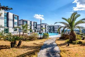 a resort with a swimming pool and palm trees at Donnaekohill Resort in Seogwipo