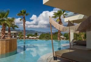 a swimming pool with palm trees and a hammock at Perla Del Mare in Alikanas