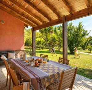 a table on a patio with people walking in the grass at Le Maquis Plage Corse in Poggio-Mezzana