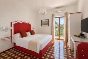 a bedroom with a bed with a red headboard and a desk at Il Canneto in Positano