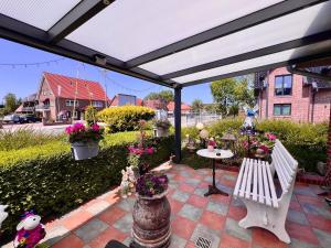 a pergola with a white bench and flowers at Pension Dang in Norddeich