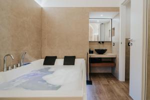 a bathroom with a tub and a sink at Saffi Suites in Noto