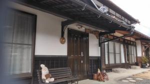 a teddy bear sitting on a bench in front of a house at Minpaku Nambu in Koka