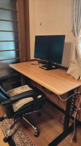 a computer monitor sitting on a desk with a chair at Minpaku Nambu in Koka