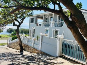 a white house with a white fence and a tree at Authentic Mossel Bay in Mossel Bay
