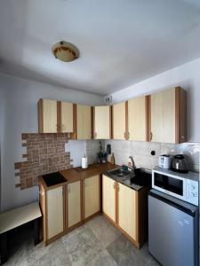 a kitchen with wooden cabinets and a brick wall at Apartman Tafra1 in Igalo