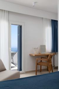 a bedroom with a bed and a desk and a window at Stunning View Sarakiniko Villa in Agios Petros