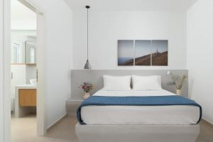 a white bedroom with a bed with a blue blanket at Stunning View Sarakiniko Villa in Agios Petros