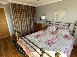 a bedroom with a bed with a blanket and pillows at The Captains Achmelvich in Lochinver