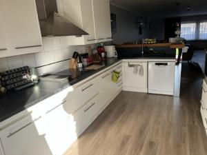a kitchen with white cabinets and a wooden floor at Room 1 km from tomorrowland in Boom