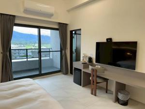 a bedroom with a bed and a desk with a television at 穗眠民宿SnoozeInn in Chishang