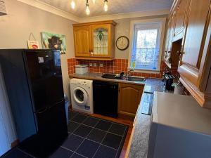 a kitchen with a black refrigerator and a dishwasher at The Captains Achmelvich in Lochinver