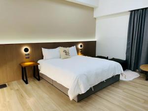 a bedroom with a large white bed and a wooden floor at 穗眠民宿SnoozeInn in Chishang
