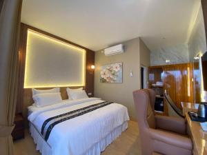 a hotel room with a large bed and a chair at Blessing Hotel Pandan in Halangan