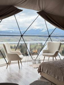two chairs and a bed in a room with a view at Forest glamp in Yasinya