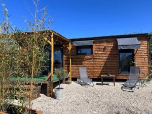a log cabin with two chairs and a table at La Tiny du Clos Ernest in Cheminot