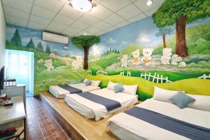 a room with three beds and a mural of animals at Fumigate Hotel in Hengchun South Gate