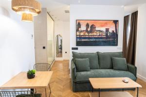 a living room with a green couch and a table at OIKOS APARTAMENTOS TURÍSTICOS in Monesterio