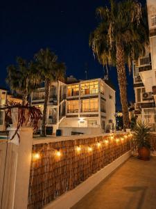 a building with lights on a fence with palm trees at Caballito del Mar apartment in Punta Prima +43 photos