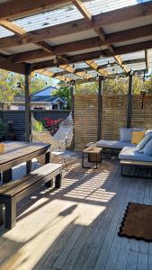 a wooden patio with a picnic table and a couch at Urban Cottage in Masterton