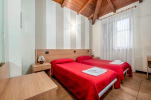 two beds in a room with red sheets at Appartamenti Residence Montebello, relax con giardino e piscina in Bolano +156 photos