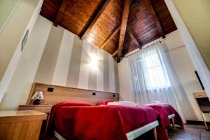 a bedroom with red blankets on a bed with a window at Appartamenti Residence Montebello, relax con giardino e piscina in Bolano