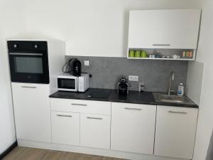 a kitchen with white cabinets and a microwave and a sink at GrafOne Apartment in Waizenkirchen