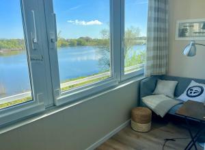 a room with three windows with a view of a lake at lüttjeseeblick13 in Nordstrand