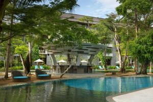 a swimming pool with chairs in front of a building at Courtyard by Marriott Bali Nusa Dua Resort in Nusa Dua