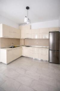 a kitchen with white cabinets and a stainless steel refrigerator at Mare Nostrum Residence in Shëngjin