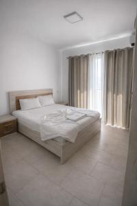 a white bedroom with a bed and a large window at Mare Nostrum Residence in Shëngjin