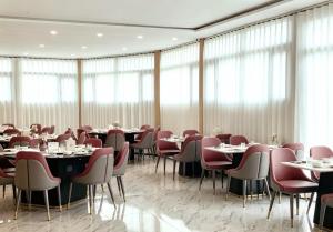 a dining room with tables and chairs and windows at Hotel Kyson 凯森酒店 in Cocody