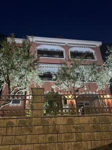 a pink building with trees in front of a wall at Radonjić Apartments in Kotor