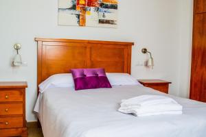 a bed with a purple pillow on top of it at Casa Corralazos in Castril