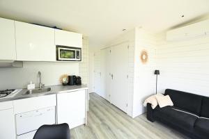 a kitchen with white cabinets and a black couch at Chalet Zijdewind in Zijdewind