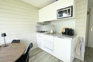 a white kitchen with a table and a microwave at Chalet Zijdewind in Zijdewind