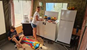 a woman standing in a kitchen next to a boy at glamping bravatents in Blanes