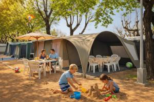 two children playing in the sand in front of a tent at glamping bravatents in Blanes