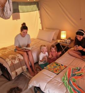 a woman and two children sitting on a bed at glamping bravatents in Blanes