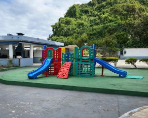 a playground with a slide in a park at Apto pe na areia 3 dorm ar cond in Caraguatatuba