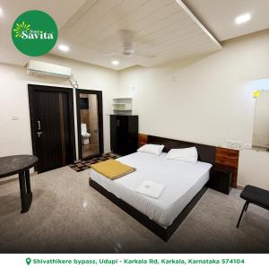 a bedroom with a bed and a desk and a table at Hotel savita in Kārkāl