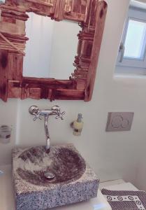 a bathroom with a stone sink with a mirror at Palio Karnagio Παλιό Καρνάγιο in Koufonisia +29 photos