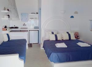 a white and blue bedroom with a bed and a kitchen at Palio Karnagio Παλιό Καρνάγιο in Koufonisia