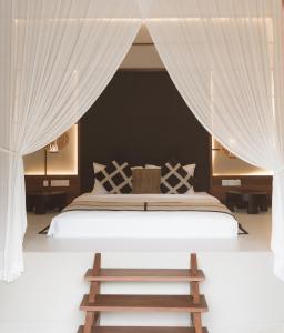 a bedroom with a large bed with white curtains at YŪN Uluwatu in Uluwatu +201 photos