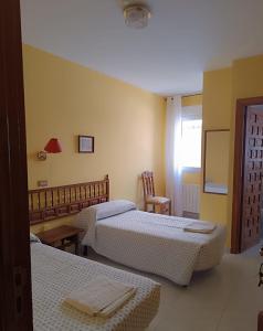 a hotel room with three beds and a mirror at Hostal Restaurante Yagual in Sahagún
