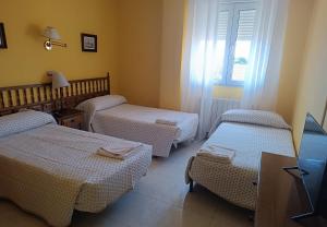 a room with three beds and a window at Hostal Restaurante Yagual in Sahagún