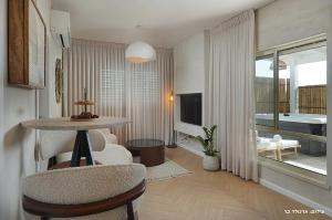 a room with a table and chairs and a living room at Shilo Boutiqe Suites in Mishmār Hāyardin
