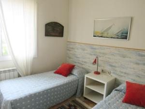 a bedroom with two beds and a table with a lamp at Casa adosada en Calella de Palafrugell in Palafrugell