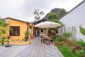 a house with a patio with an umbrella and tables and chairs at Dreamy Homestay in Xuân Sơn
